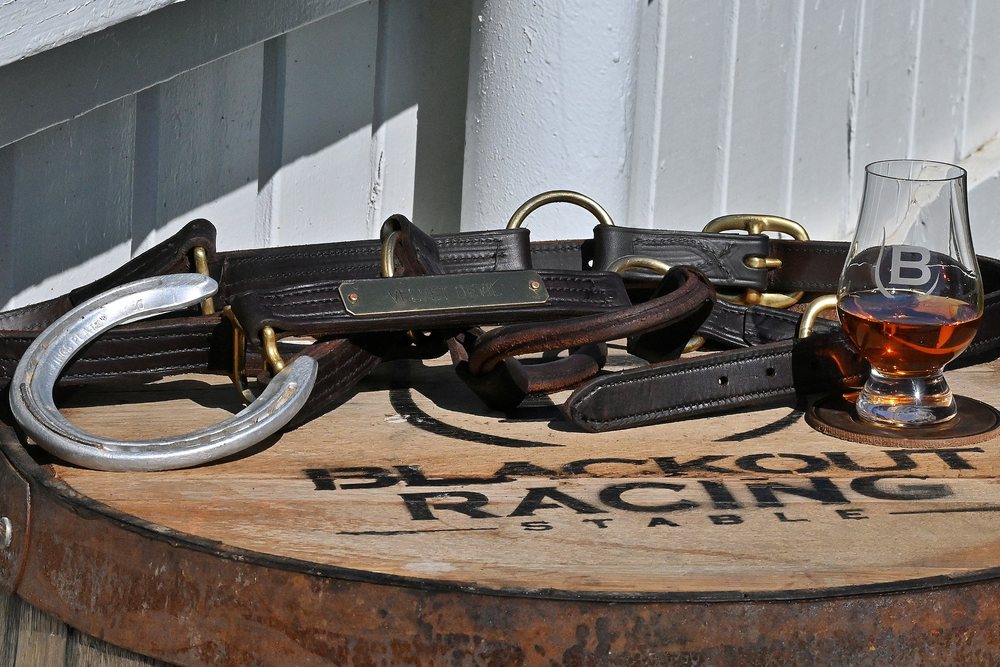 Halters, a horseshoe and a whiskey glass on a barrelhead
